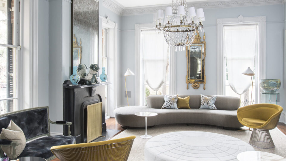 Interior design of a bright, elegant living room with vintage decor and large windows.